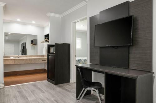 a bathroom with a desk with a television on a wall at Motel 6-Anaheim, CA - Convention Center in Anaheim