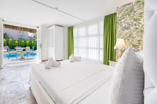 a white bedroom with green curtains and a large bed at ALAÇATI ROKA TAŞ BUTİK HOTEL in Çeşme
