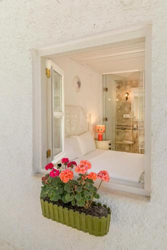 a bedroom with a bed with red flowers in a window at ALAÇATI ROKA TAŞ BUTİK HOTEL in Çeşme