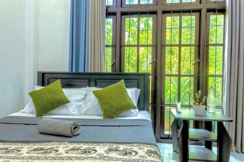 a bedroom with a bed with green pillows and a table at Hill Top Villa Kandy in Ambatenna