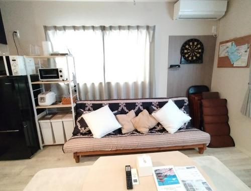 a living room with a couch with pillows and a window at Hachi Kamakura KOIWA in Tokyo