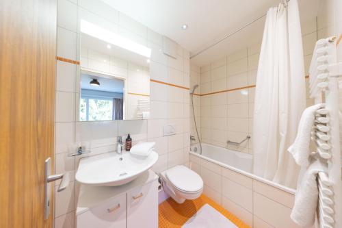 a white bathroom with a sink and a toilet at Alpenblick-Apartment mit Pool & Sauna in St. Moritz