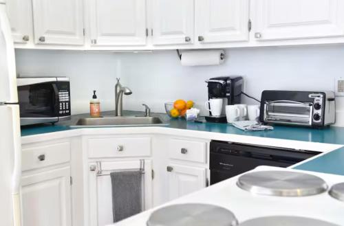 a kitchen with white cabinets and a sink and a microwave at Downtown Suite #4 - Wharf View in Newport