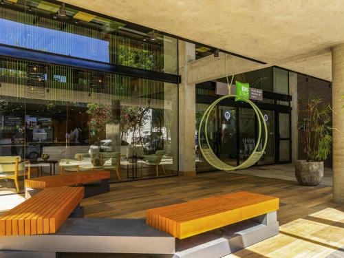 a lobby with benches and tables in a building at ibis Styles Porto Alegre Moinhos de Vento in Porto Alegre