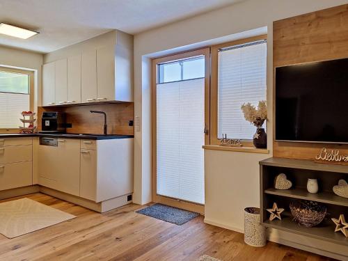 a kitchen with white cabinets and a flat screen tv at Apartment A3 by Interhome in Kematen in Tirol