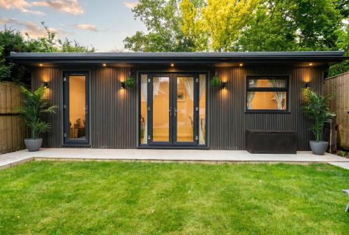 a black tiny house with a green yard at Garden Studio in Hove, Parking & Hot Tub in Brighton & Hove