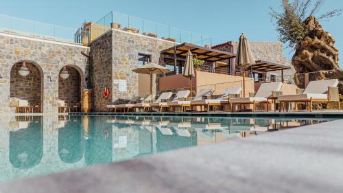 a swimming pool with chairs and umbrellas next to a building at Volta Seaside Boutique Hotel in Kokkini Khanion