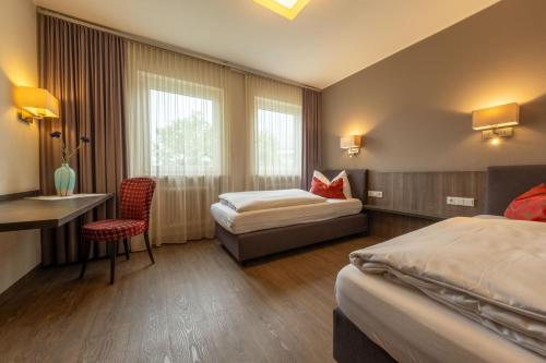 a hotel room with two beds and a desk at Hotel Staffler in Odelzhausen