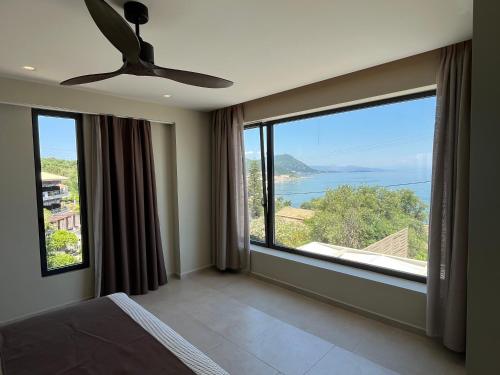 a bedroom with a large window with a view of the ocean at Palms and Spas Villas Retreat in Mesongi
