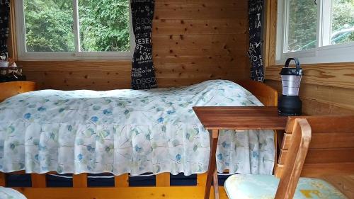 a bedroom with a bed and a table and windows at こや・かやき in Yufu