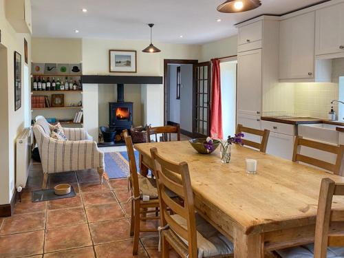 a kitchen and living room with a wooden table and a fireplace at Ardtur Croft in Appin