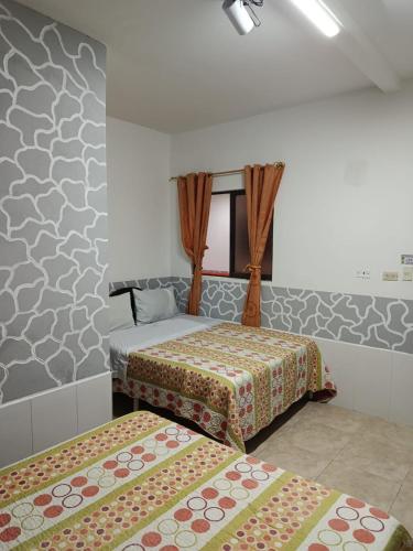 a bedroom with two beds and a wall with patterns at HOTEL DEL PARQUE VELEZ Santander in Vélez