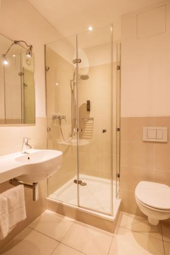 a bathroom with a shower and a toilet and a sink at Hotel Staffler in Odelzhausen