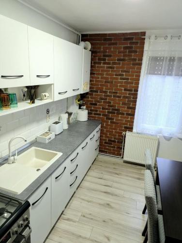 a kitchen with white cabinets and a brick wall at Ariana Urban Loft in Târgu-Mureş