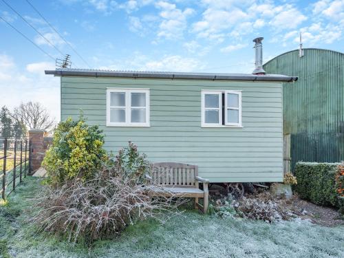 a green house with a bench in front of it at Shepherds Hut - Uk45529 in Buildwas