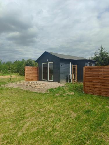 a blue house with a fence in a yard at Na Kocankach - Domki na wyłączność in Czarnoszyce