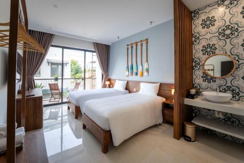 a hotel room with two beds and a balcony at Maison De Hoi An Boutique Homestay in Hoi An