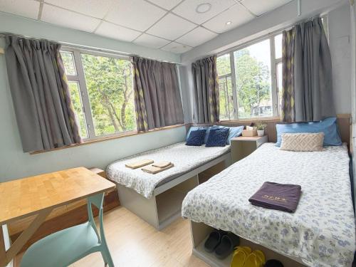 a small room with two beds and a table at AMU Dreamhouse 阿木旅舍 in Hong Kong