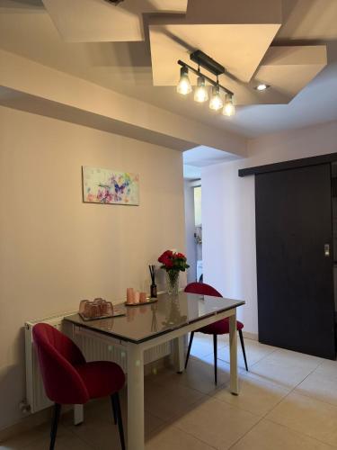 a dining room with a table and red chairs at GZP Residence Lugoj 6 in Lugoj