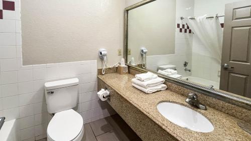 a bathroom with a toilet and a sink and a mirror at Studio 6 Suites Houston, TX - Spring in Houston