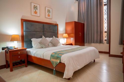 a bedroom with a large bed with a nightstand and a bed sidx sidx sidx at Rostel Villa Hotel in Mbeya