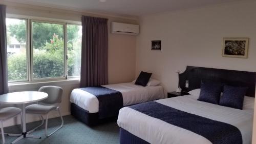 um quarto de hotel com duas camas e uma mesa e uma janela em Ararat Southern Cross Motor Inn em Ararat