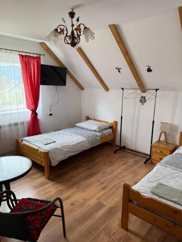 a bedroom with two beds and a table and a window at Pokoje Przy Szlaku Agroturystyka in Żabnica
