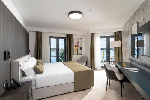 a bedroom with a bed and a desk and chairs at Visula Hotel & Spa - New Opening 2026 in Medulin