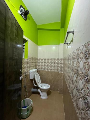a bathroom with a toilet and a green ceiling at Hotel Diyo inn in Guwahati