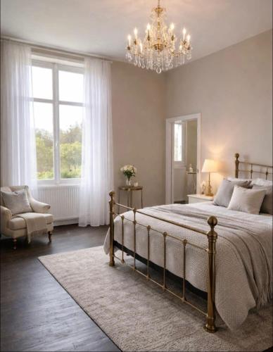a bedroom with a large bed and a chandelier at Le clos joli in Saint-Saviol
