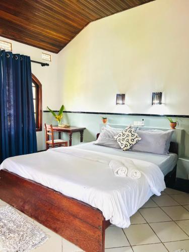 a bedroom with a large bed with white sheets at Sunny's Garden Hotel in Ambalangoda