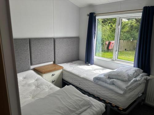 two beds in a small room with a window at Newquay - Deluxe 3 bed Lodge Willows Way 47, Newquay Parkdean, Holiday Park in Newquay
