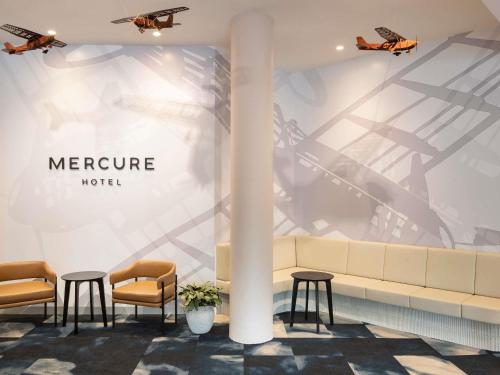 a lobby with two chairs and a couch and two planes at Mercure Sydney Bankstown in Bankstown