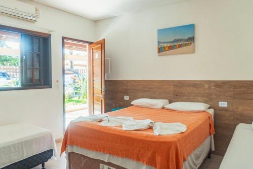 a bedroom with a bed with an orange blanket at Pousada Acqua Bella PISCINA CLIMATIZADA in Bertioga