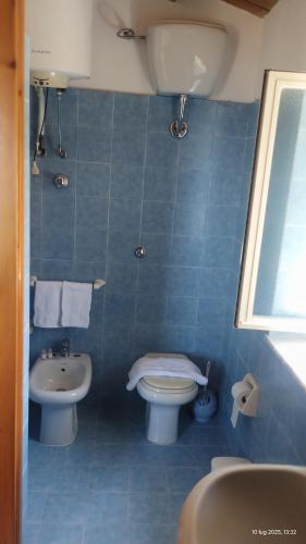 a blue tiled bathroom with a toilet and a sink at Casa vacanze Torre in Cefalù