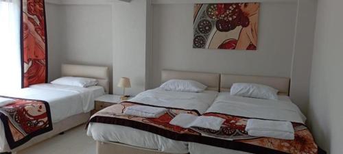 a bedroom with two beds and a picture on the wall at Ayışık Otel in Hamidiye