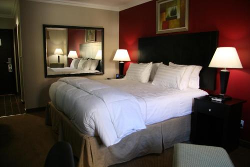 a large bed in a hotel room with a mirror at Hampshire Hotel - Ballito in Ballito
