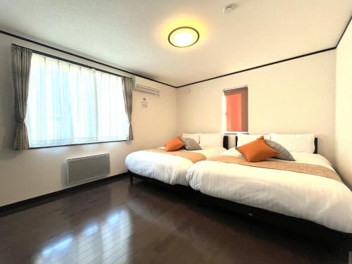 two beds in a room with two windows at Stay923 in Asahikawa