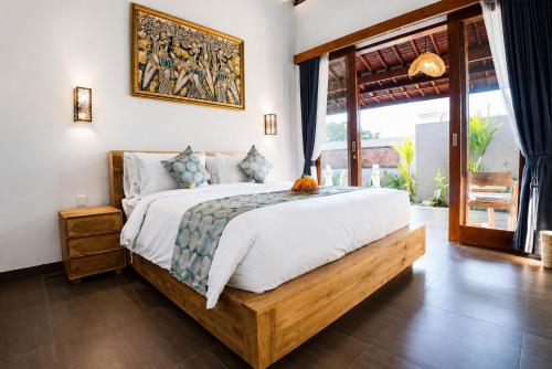 a bedroom with a large bed with a picture on the wall at Ardinia Villa Ubud Private Pool in Ubud