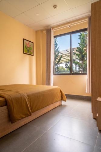 a bedroom with a bed and a large window at DaLaHa City in Da Lat