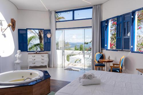 a bedroom with a tub and a large window at Ilhas Gregas Chalets in Lavras Novas