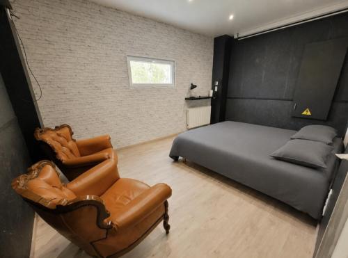 a bedroom with a bed and a leather chair at Le Refuge Gabriel avec grand parking privé in Blois