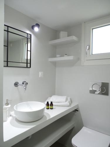 a white bathroom with a sink and a mirror at ÉLYSÉE Boutique in Katavatí