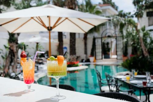 two cocktails sitting on a table next to a pool at Elegance East Hotel in Antalya