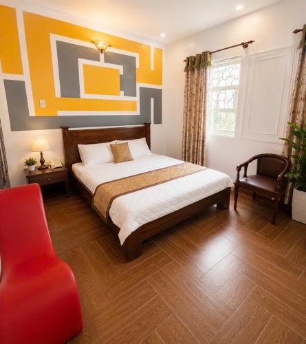 a bedroom with a large bed and a red chair at Nhật Vân 2 in Ho Chi Minh City