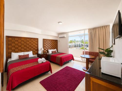 a hotel room with two beds and a flat screen tv at Zona Dorada Living in Mazatlán