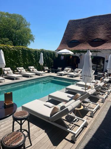 a group of lounge chairs next to a swimming pool at The Cotton Suites B&B in Deerlijk
