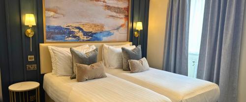 a bedroom with a bed with white sheets and pillows at Trouville Bournemouth - OCEANA COLLECTION in Bournemouth