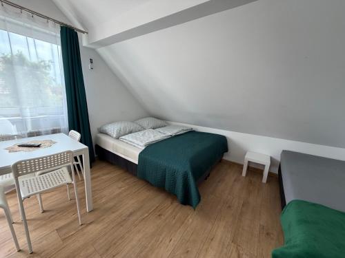 a small bedroom with a bed and a table at Przystanek Zator in Zator