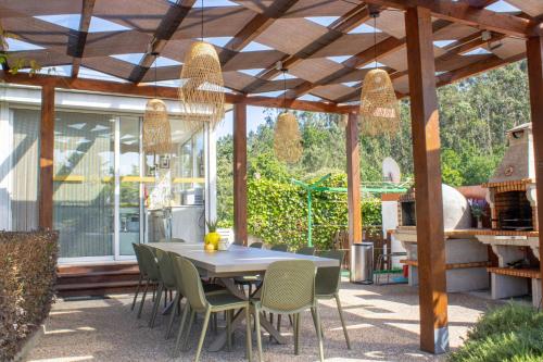 a patio with a table and chairs under a wooden pergola at Fulão Nature Living in Barcelos